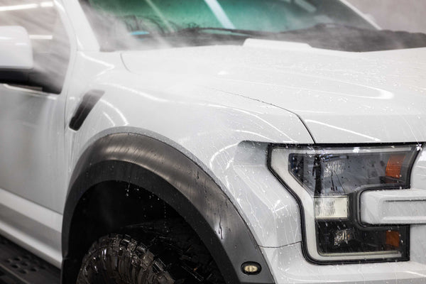Water being sprayed onto a white vehicle.