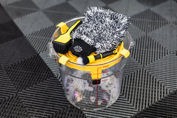 Detail Factory Clean Screen Livewire placed on top of a clear wash bucket, holding detailing brushes and a microfiber wash mitt.