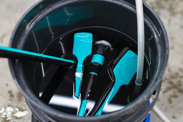 Detail Factory Fender Well Brush Riptide and tools in a bucket filled with water.