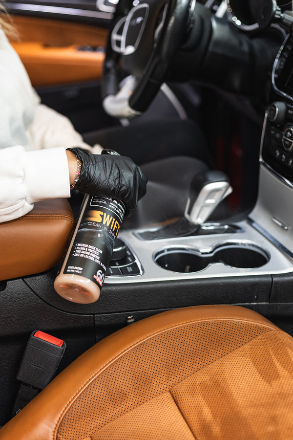 Person spraying P&S Swift on a car's cupholder.
