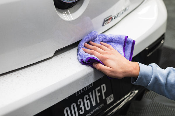 Person cleaning a white car with a purple minx royale.