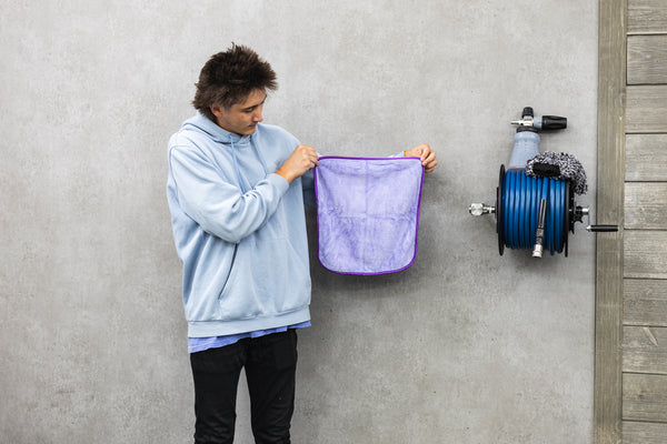 Person holding a purple minx royale in front of a grey wall.