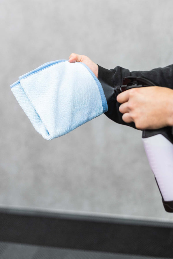 Person spraying a blue FTW microfiber with an iK Sprayer.