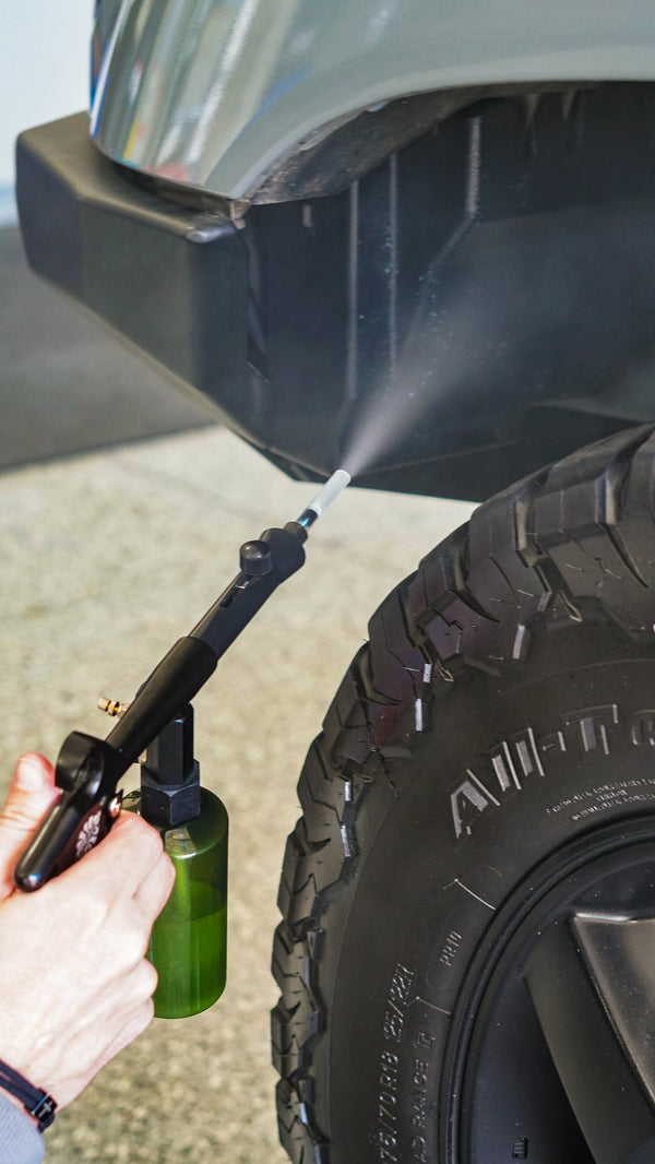 A person using The Rag Company Ultra Aire Spray Applicator to clean the wheel well.