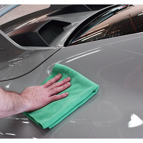 Using a Pearl towel from The Rag Company in a green color, measuring 16 inches by 16 inches, to detail the exterior of a grey sports car.