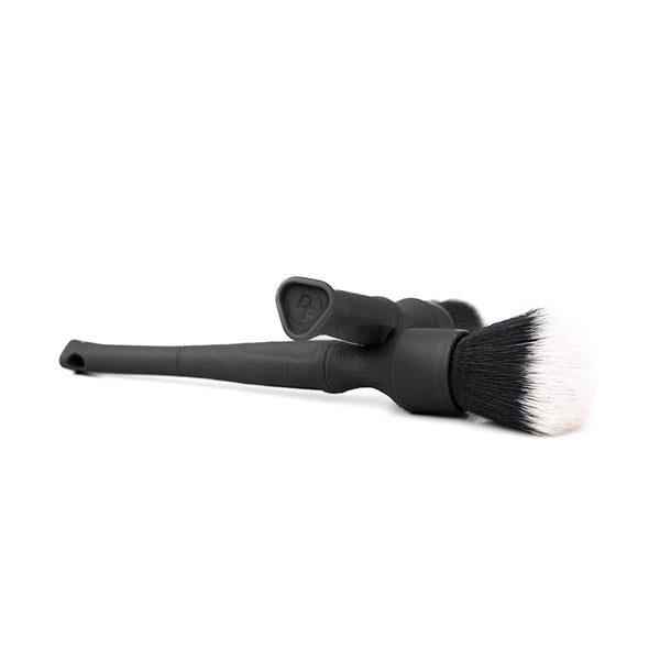 Two black Detail Factory Synthetic Brushes crossing on a white background.
