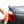 A closeup of a person wiping the back headlight of a grey car with an orange towel.