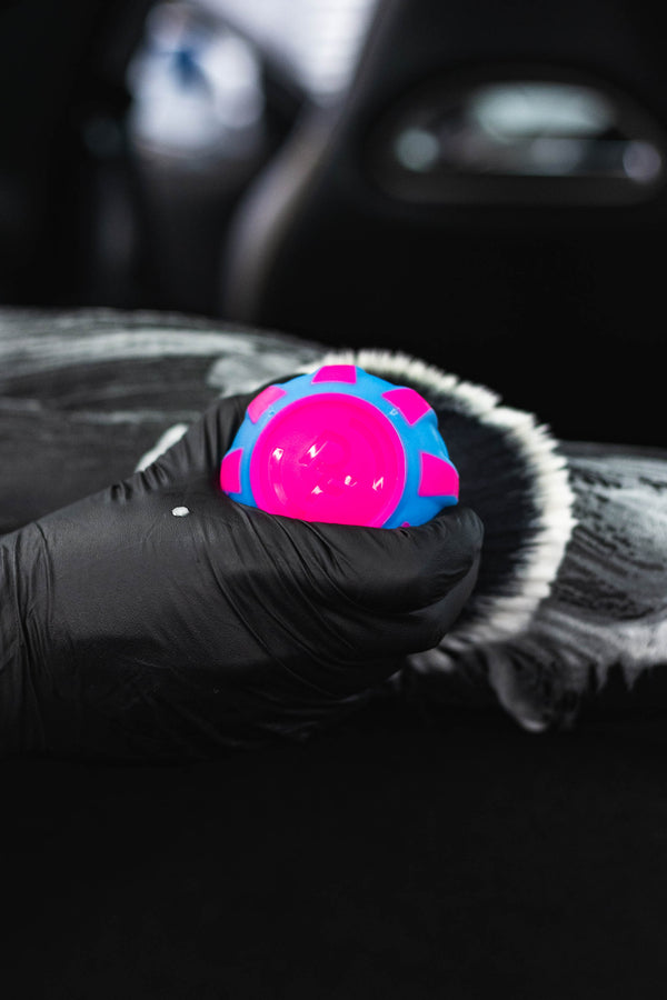 Person cleaning car interior with a Detail Factory Curveball Underglow.