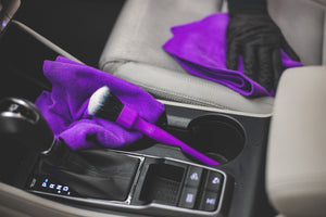 Detail Factory Ultra Soft Purple brush and microfiber towel inside of a car cupholder.