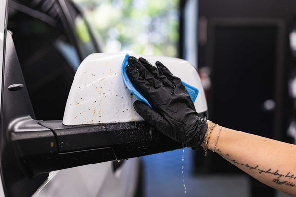Gtechniq W8 Bug Remover being used with a Jersey Bug Scrubber on a white truck side mirror.