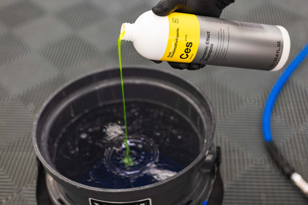 Pouring Koch-Chemie Ceramic Effect shampoo into a black bucket full of water. 