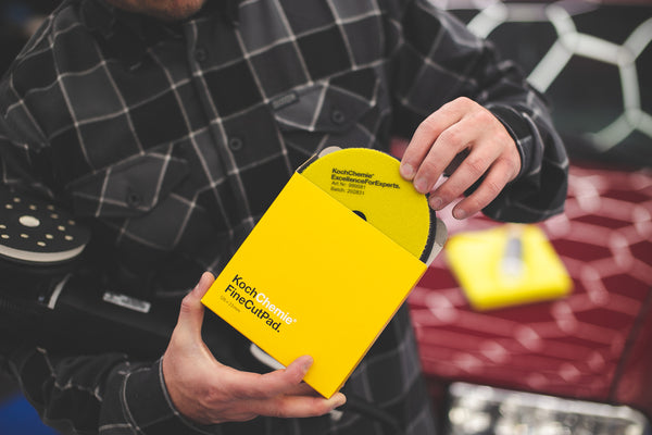 A person taking a KochChemie Fine Cut Pad 126mm from the packaging.