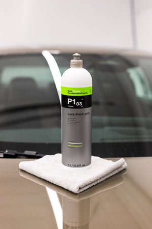 Koch Chemie Lack Polish Grun P1.03 1 Liter bottle sitting on a white towel on top of the hood of a car.