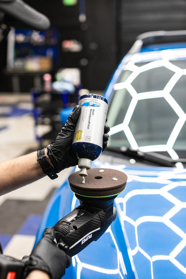 A person pouring KochChemie ShineSpeedPolish onto a KochChemie Polish and Sealing pad attached to a Rupes Polisher.