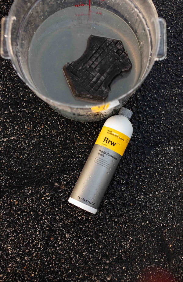 Koch-Chemie Rapid Rinseless Wash 1 Liter bottle laid next to a bucket of water with a black sponge. 