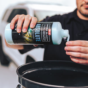 A person pouring P and S Absolute into it's cap over a black bucket.