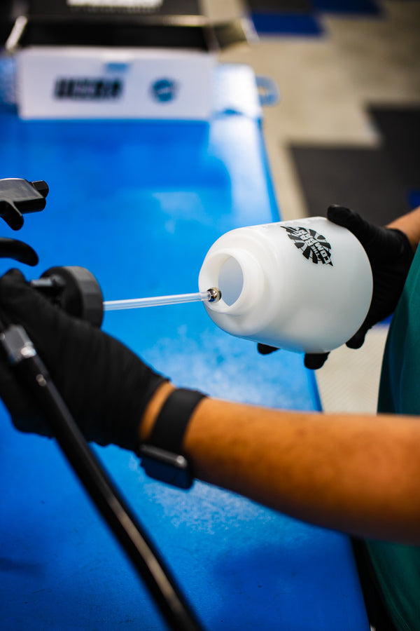 A person putting the sprayer onto the water reservoir of The Rag Company Ultra Air Engine blaster with a blue car in the background.  