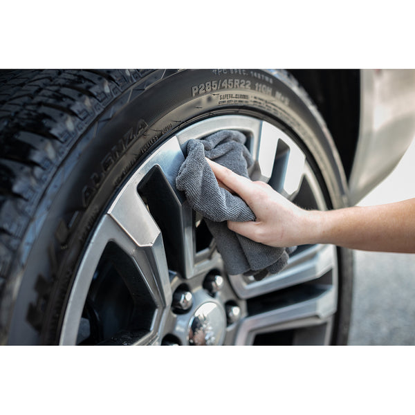 The Rag Company Miner grey towel wiping a tire rim. 