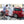 A person using a large IK Sprayer to spray foam onto a red vehicle.