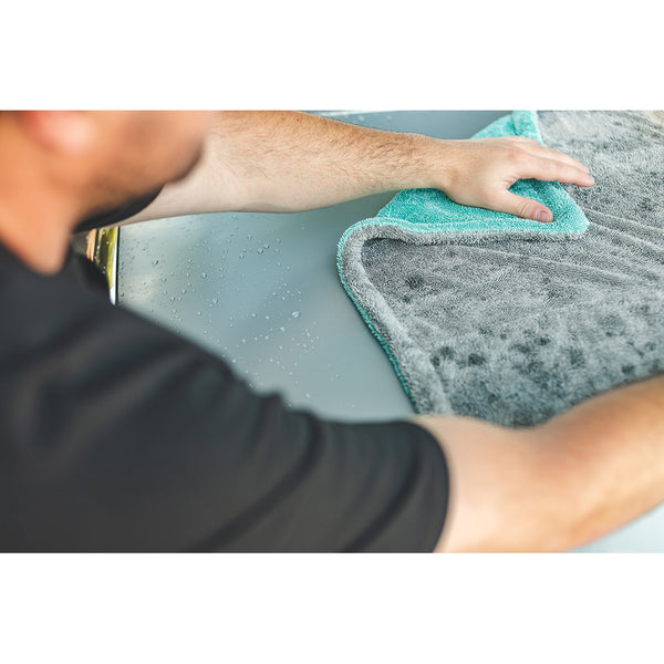 A closeup of a person spreading a liquid8r towel across the hood of a car.
